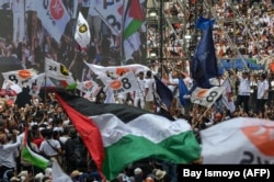 Pendukung mengibarkan bendera Palestina saat puluhan ribu pendukung calon presiden dan wakil presiden, Anies Baswedan dan Muhaimin Iskandar, menghadiri kampanye di Jakarta International Stadium, Jakarta pada 10 Februari 2024. (Foto: AFP/Bay ismoyo)