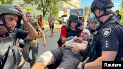Police officers and paramedics transport an injured man at the site of a Russian airstrike in Kharkiv, Ukraine, June 30, 2024.