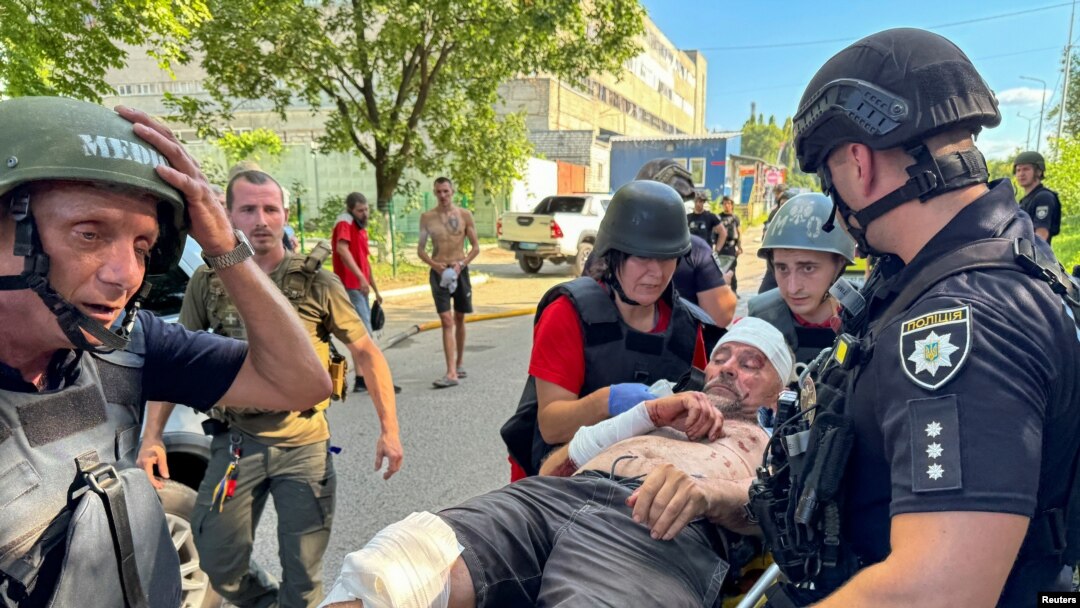 Anggota kepolisian dan sejumlah paramedis membawa seorang pria yang terluka di lokasi serangan yang dilancarkan pasukan Rusia di Kharkiv, Ukraina, pada 30 Juni 2024. (Foto: Reuters/Vitalii Hnidyi)