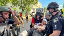 Anggota kepolisian dan sejumlah paramedis membawa seorang pria yang terluka di lokasi serangan yang dilancarkan pasukan Rusia di Kharkiv, Ukraina, pada 30 Juni 2024. (Foto: Reuters/Vitalii Hnidyi)