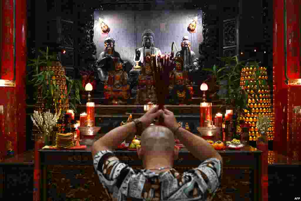 A man offers prayers at Satya Dharma temple in Denpasar on Indonesia&#39;s resort island of Bali, on the eve of the Lunar New Year of the Dragon. (Photo by SONNY TUMBELAKA / AFP)