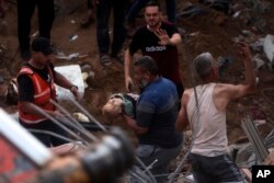 Palestinians carry a dead child was found under the rubble of a destroyed building following Israeli airstrikes in Nusseirat refugee camp, central Gaza Strip, Oct. 31, 2023.