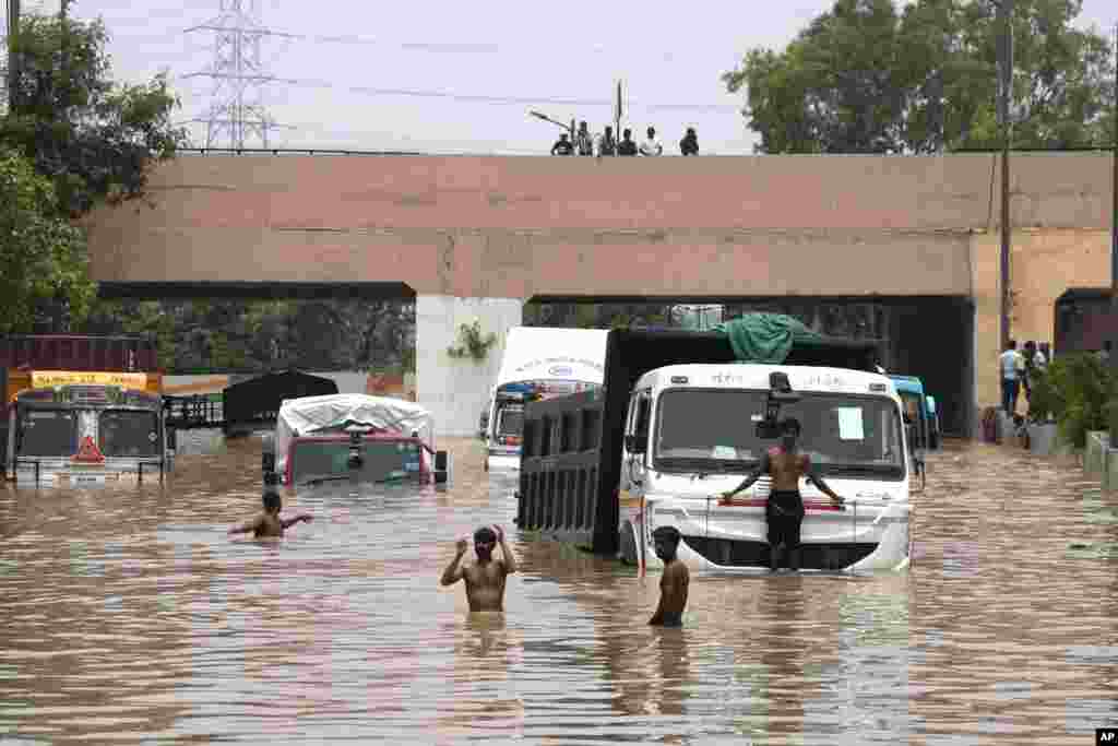 Beberapa kendaraan berusaha melewati jalan bawah tanah yang banjir setelah hujan lebat di ibu kota New Delhi, India.