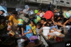 Palestinians jostle one another as they wait for food to be distributed in Rafah, southern Gaza Strip, Nov. 8, 2023.
