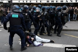 FILE - French riot police apprehend a protester amid clashes during a demonstration as part of nationwide strikes and protests against French government's pension reform, in Paris, March 23, 2023.