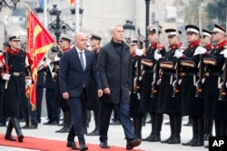 NATO Secretary-General Jens Stoltenberg, center, accompanied by North Macedonia's Prime Minister Dimitar Kovacevski, center left, review the honor guard squad at the Government building in Skopje, North Macedonia, Nov. 21, 2023.