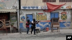 Police officers take cover during an anti-gang operation in the Portail neighborhood of Port-au-Prince, Haiti, April 25, 2023.