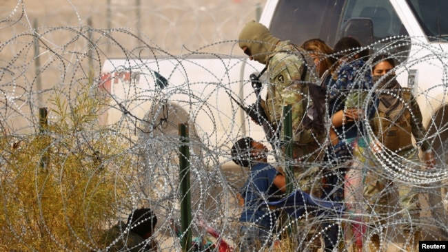 FILE - A migrant child seeking asylum kneels in front of a member of the Texas National Guard and asks to be allowed to enter the United States, as seen from Ciudad Juarez, Mexico, Jan. 30, 2024.