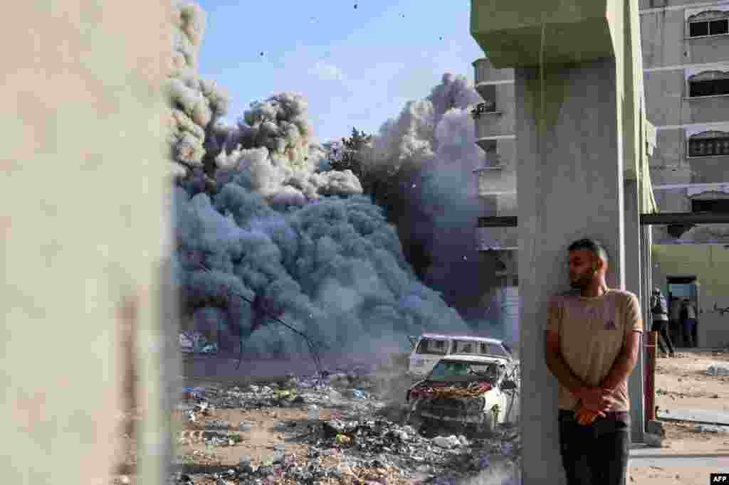 A man takes cover behind a column as an explosion propagates smoke and dust during an Israeli strike which reportedly targeted a school in the Zeitoun district on the outskirts of Gaza City.