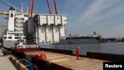 FILE - An autotransformer intended for the expansion of the Lithuanian-Polish electricity system connection LitPol Link is loaded on a barge in the port of Klaipeda, Lithuania, May 13, 2021.