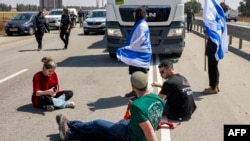 Протестующие израильтяне блокируют дорогу иорданским грузовикам с гуманитарной помощью, прибывающим на израильскую сторону пограничного перехода Керем-Шалом с сектором Газа, 16 апреля 2024 года (Photo by Menahem Kahana/AFP).