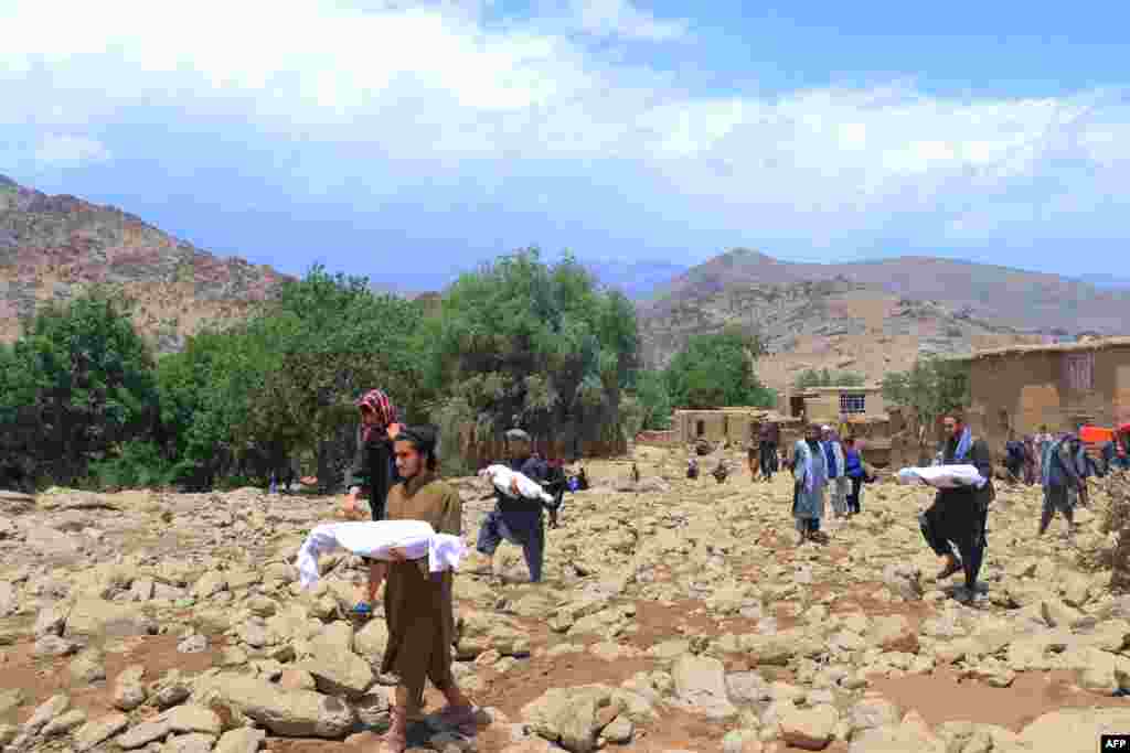 Afghan residents carry the bodies of children, who died in flash floods in the Jalrez district of Maidan Wardak province.