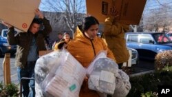 Carolina Gonzalez of Venezuela carries supplies into the Chicago City Life Center, Nov. 29, 2023, in Chicago. 