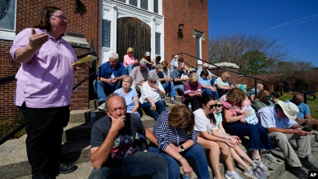 Rev. Mary Stewart, left, of Rolling Fork United Methodist Church, leads a prayer as people affected by Friday's tornado worship on the steps of the church, in Rolling Fork, Mississippi, March 26, 2023.