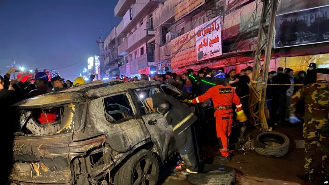 Civil defense members gather at the site of a burned vehicle targeted by a U.S. drone strike in east Baghdad, Iraq, Feb. 7, 2024. 