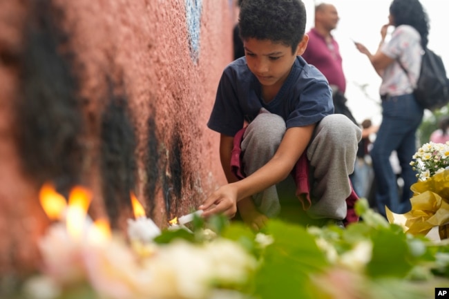 FILE - A student from the Thomazia Montoro public school lights a candle during a vigil asking for peace the day after a student stabbed a teacher to death at the school in Sao Paulo, Brazil, March 28, 2023. (AP Photo/Andre Penner, File)