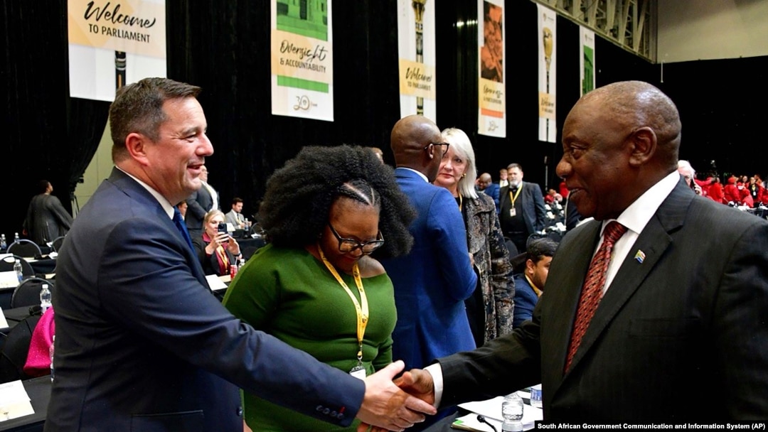 FILE - South African President Cyril Ramaphosa, right, greets opposition Democratic Alliance (DA) leader, John Steenhuisen, left, at the first sitting of Parliament since elections, in Cape Town, June 14, 2024. 