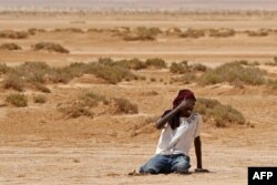 Un migrant d'origine africaine s'effondre d'épuisement et de déshydratation à son arrivée dans une zone inhabitée près d'al-Assah à la frontière libyo-tunisienne, le 30 juillet 2023.