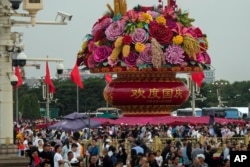 Visitors gather near giant flower baskets on display in busy Tiananmen Square to celebrate the 74th anniversary of the founding of the People's Republic of China, in Beijing, Thursday, September 28, 2023. (AP/Andy Wong)