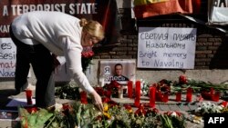 A woman places flowers in front of the Russian embassy in Madrid on February 17, 2024, one day after Russian officials announced the death of the Kremlin's most prominent critic Alexei Navalny.