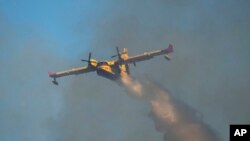 A Canadair aircraft drops water over a wildfire in Vati village, on the Aegean Sea island of Rhodes, southeastern Greece, on July 25, 2023. Two Greek air force pilots died when their plane crashed on the island of Evia after dropping water on a fire.