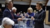 French President Emmanuel Macron casts his ballot flanked by French first lady Brigitte Macron at a polling station to vote in the second round of French parliamentary elections in Le Touquet-Paris-Plage, July 7, 2024. 