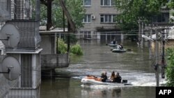 Volunteers in boats assist during an evacuation from a flooded area in Kherson, Ukraine, June 8, 2023, following damage sustained at the Kakhovka hydroelectric power plant dam.