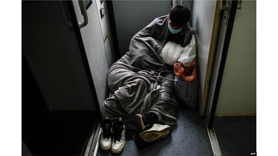 A couple rests on the floor as they ride a train from Beijing to Shijiazhuang on Feb. 6, 2024.