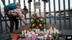 Seorang anak perempua menyalakan lilin untuk mengenang para korban kebakaran di pusat penahanan imigrasi yang menewaskan puluhan orang di Ciudad Juarez, Meksiko, Selasa, 28 Maret 2023. (AP/Christian Chavez)