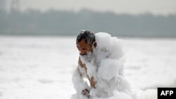 A man bathes in the polluted waters of river Yamuna laden with foam in New Delhi, India.