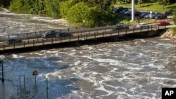 Water flows dangerously high under a bridge at Falls Park in Sioux Falls, South Dakota, June 22, 2024, after days of heavy rain led to flooding in the area.