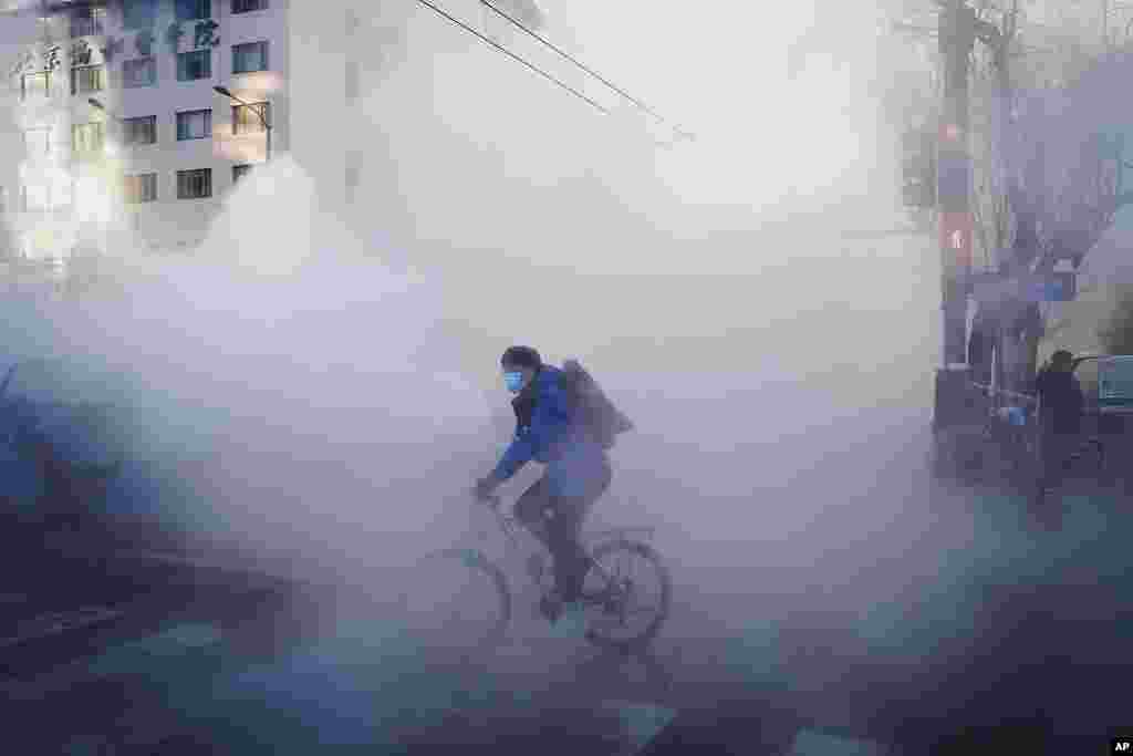 A cyclist rides through the steam leak of the water heating network in Dongcheng district during the morning rush hour in Beijing. Temperatures has plunged across northern China.