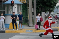 Petugas lalu lintas Ramiro Hinojas, berpakaian Sinterklas, mengarahkan kendaraan di sepanjang Macapagal Avenue di Pasay, Metro Manila, 28 November 2023. (JAM STA ROSA / AFP)