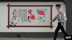 一名女子走过北京街头的一面中国政府宣传社会主义核心价值观的宣传墙。（2021年6月9日）