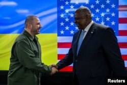 U.S. Defense Secretary Lloyd Austin and Ukraine's Defence Minister Rustem Umerov shake hands after their meeting, in Kyiv, Ukraine, Nov. 20, 2023. (Ukraine's Defence Minister Rustem Umerov via X/Handout via Reuters)