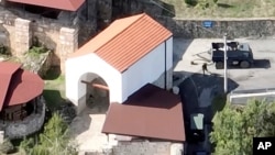 This photo taken by a drone on taken on Sept. 24, 2023, shows an armed man at the entrance of the Banjska monastery in Kosovo. 