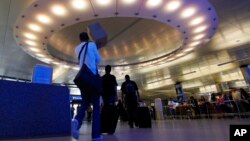 FILE - Arriving international passengers pass under a 'halo' of light at the customs clearance area at the Tom Bradley International Terminal at Los Angeles International Airport, May 28, 2010. 