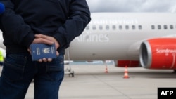 A man holds Ukrainian passports for himself and his wife while waiting at the tarmac next to the medical evacuation (Medevac) airplane at the Cologne Bonn airport in Germany on March 23, 2023.