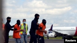 Anggota Densus 88 membawa tersangka teroris di Bandara Raden Inten, Lampung, untuk dikirim ke Jakarta pada 16 Desember 2020. (Foto: Ardiansyah/Antara Foto via Reuters)