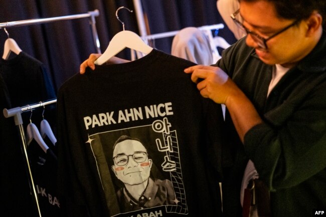 Seorang pria memegang kaos bergambar wajah calon Presiden Anies Baswedan, yang namanya diubah dari "Pak" Anies, menjadi nama yang lebih terdengar Korea "Park Ahn Nice" saat kampanye di Jakarta, 8 Februari 2024. (Yasuyoshi CHIBA / AFP)