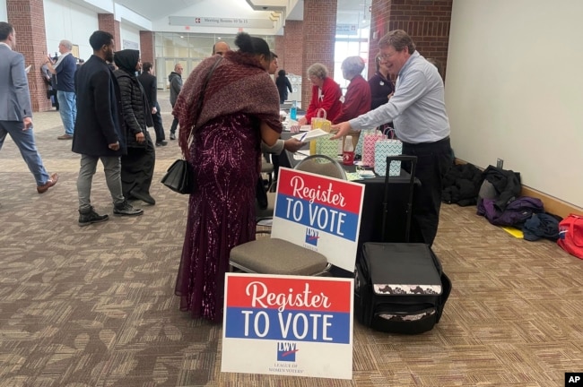 FILE - People approach a table where they can register to vote after becoming U.S. citizens during a naturalization ceremony at a convention center in St. Paul, Minn., March 9, 2023. (AP Photo/Trisha Ahmed)