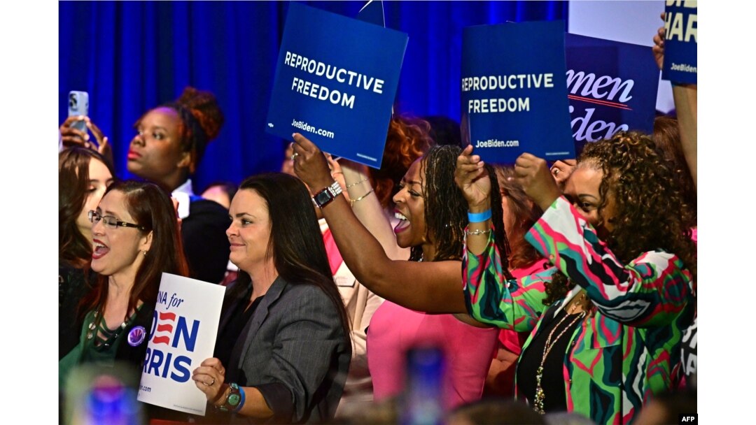 Women hold signs as they listen to Vice President Kamala Harris speak on reproductive freedom at El Rio Neighborhood Center in Tucson, Ariz., April 12, 2024.