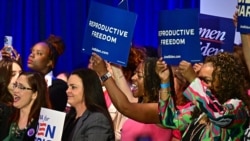 Sejumlah perempuan memegang spanduk sambil mendengarkan Wakil Presiden Kamala Harris berbicara tentang kebebasan reproduksi di El Rio Neighborhood Center, Tucson, Arizona, pada 12 April 2024. (Foto: AFP)