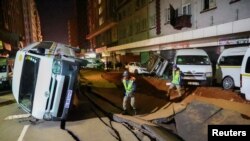 Police officers inspect damaged cars and the road after a suspected gas explosion injured people and caused significant damage, in the central business district of Johannesburg, South Africa, July 19, 2023.