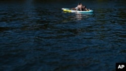People relax on paddle boards on the Willamette River in Portland, Oregon, July 5, 2024. A potentially record-setting heat wave is spreading across the western part of the United States, sending many residents searching for a cool haven.