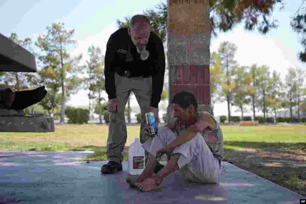 Mark Paulson, a Public Response and Code Enforcement officer, checks on Deb Billet, 66, before calling an ambulance to take her to a hospital for heat-related symptoms, July 10, 2024, in Henderson, Nevada.&nbsp;About 14 officers from the Office of Public Response drove around the city offering water, electrolytes, free bus tickets and rides to cooling centers during a heat emergency.&nbsp;