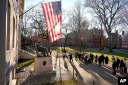 FILE - People take photographs near a John Harvard statue, left, Tuesday, Jan. 2, 2024, on the campus of Harvard University, in Cambridge, Mass. (AP Photo/Steven Senne)