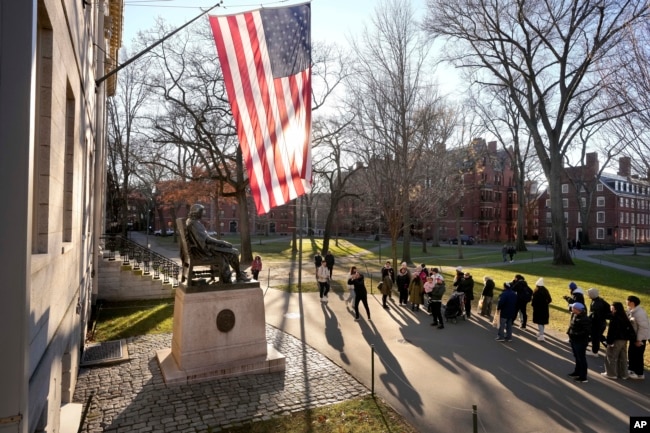 FILE - People take photographs near a John Harvard statue, left, Tuesday, Jan. 2, 2024, on the campus of Harvard University, in Cambridge, Mass. (AP Photo/Steven Senne)