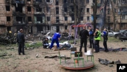 FILE - Police investigators inspect a body near an apartment complex hit in a Russian missile strike in Kryvyi Rih, Ukraine, June 13, 2023. 