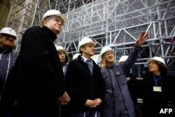 French President Emmanuel Macron, flanked by President of the public establishment 'Rebuilding Notre-Dame de Paris' Philippe Jost and Archbishop of Paris Laurent Ulrich, visits the nave of the cathedral, Dec. 8, 2023.